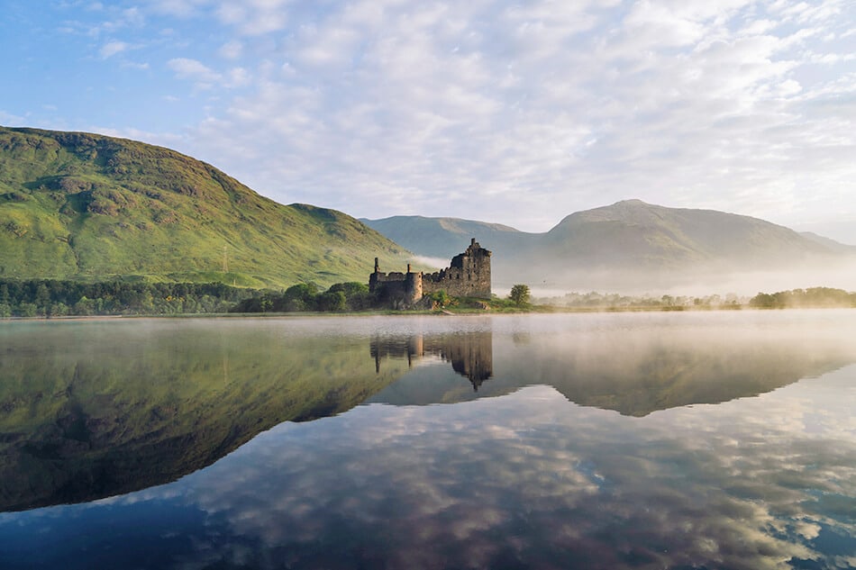 Castello scozzese nelle Highlands si riflette sulle acque di un lago