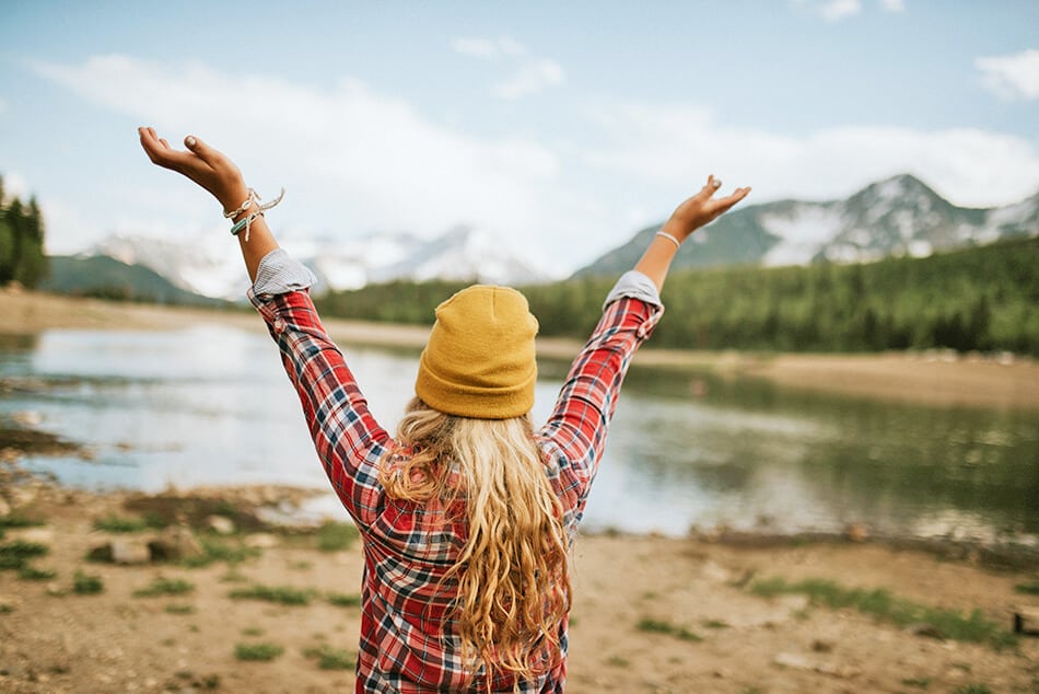 Ragazza bionda con indosso una camicia tartan nei pressi di un lago