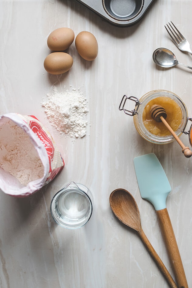 Tavolo in legno con spatole, cucchiai in legno, farina, miele e altri ingredienti