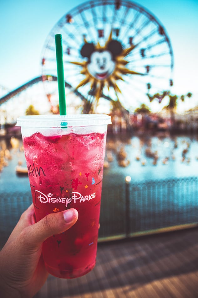 Plan a trip to Disney Park: a tall glass of strawberry juice at Disney World Orlando with the big Mickey Mouse ferris wheel on the background. | #disney #Florida