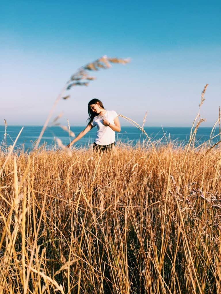 Girl wearing a white t-shirt walks in a field of wheat in Tuscany.