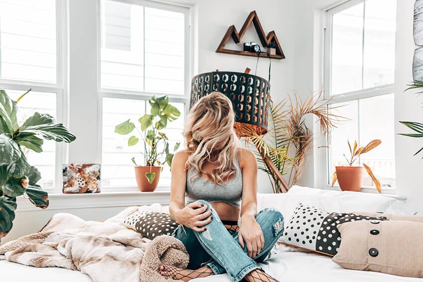 Girl having fun on a bed surrounded by art inspired pillows