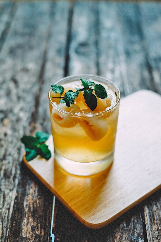 Un cocktail giallo con foglie di menta decorative a base di gin inglese