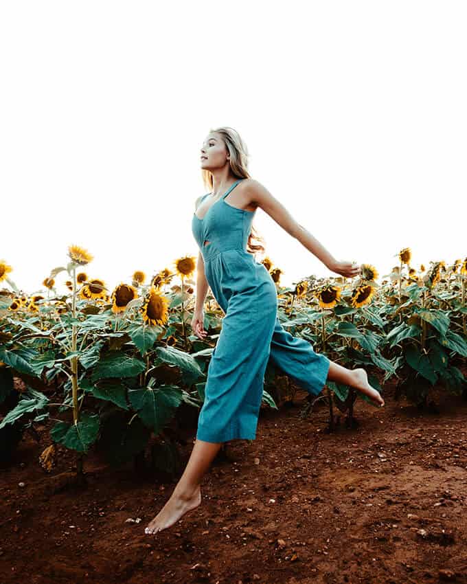 Girl jumping in a sunflower field in summer
