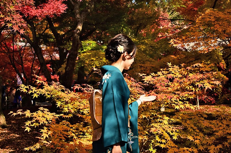 Una geisha in un parco a Tokyo in autunno