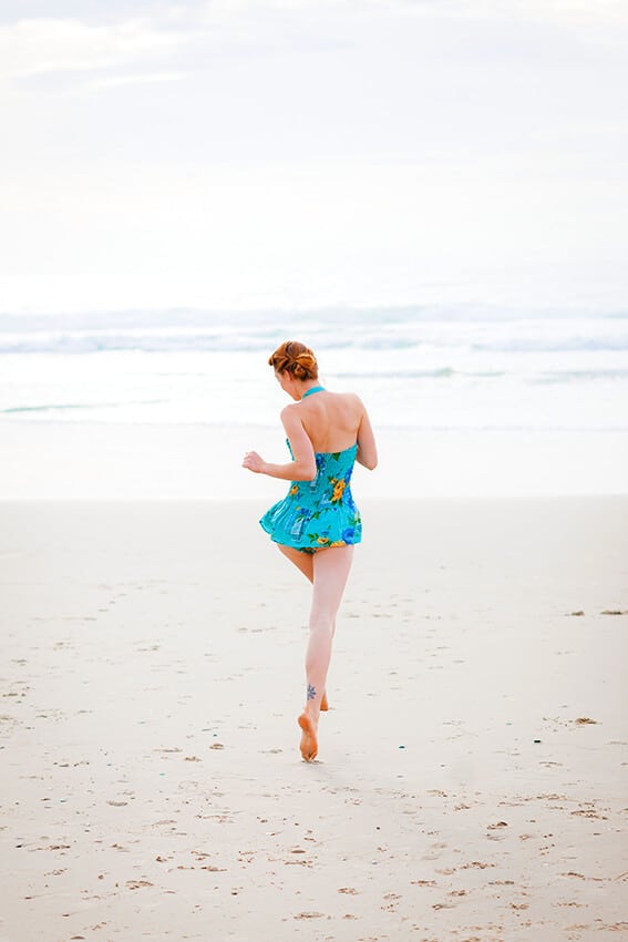 Woman having fun on the beach with a vintage baby blue swimsuit