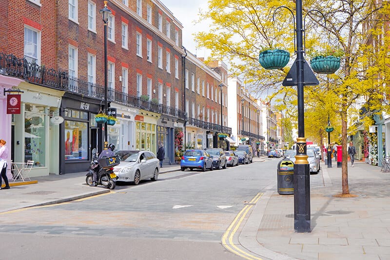 A cute street in London in Fall lined with red brick buildings and trees