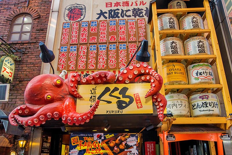 Un enorme polpo rosso avvinghiato all'insegna di un negozio che vende takoyaki a Osaka
