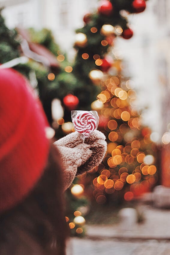 Girl enjoying her time at Christmas markets in Italy with a striped lollipop