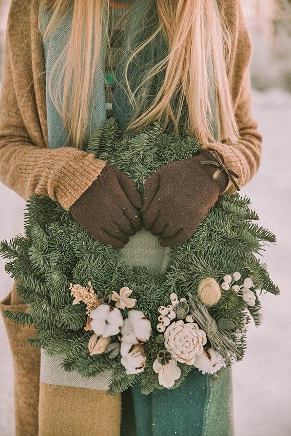 Ragazza tiene una ghirlanda natalizia tra le mani in mezzo alla neve