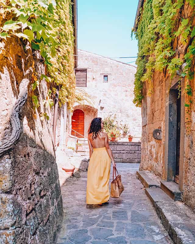 Girl with a summer dress walking through a stone village on a day trip from Florence