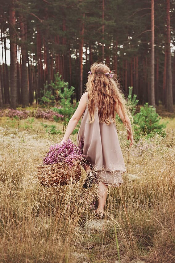 Bambina in abito tradizionale raccoglie un cesto di fiori nelle campagne irlandesi