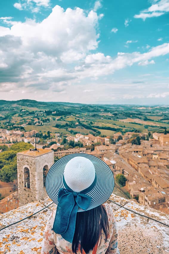 Ragazza con cappello a tesa larga guarda il panorama delle campagne toscane