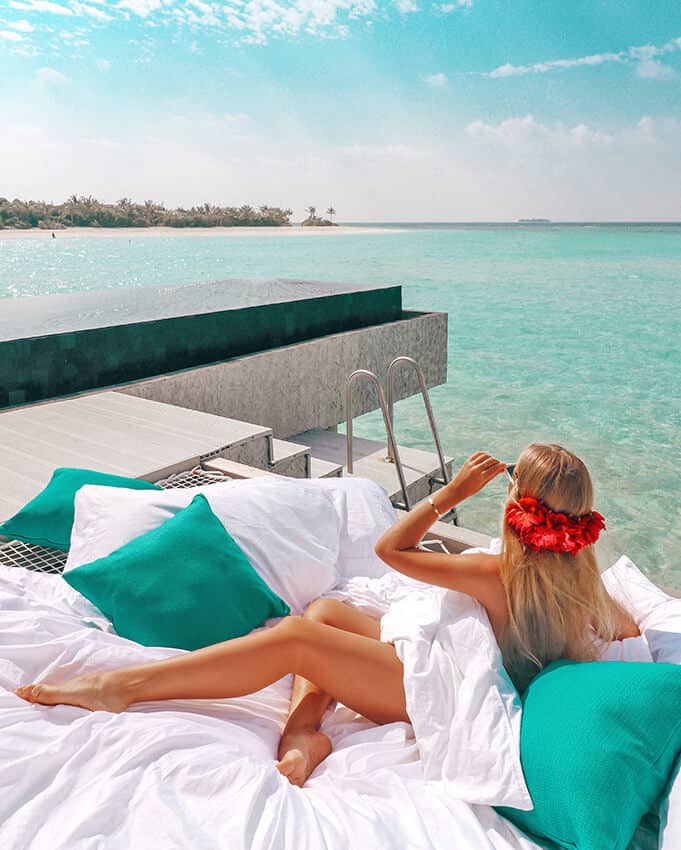 Blonde girl laying on a beachside pool while looking at one of St Thomas beaches with white sand