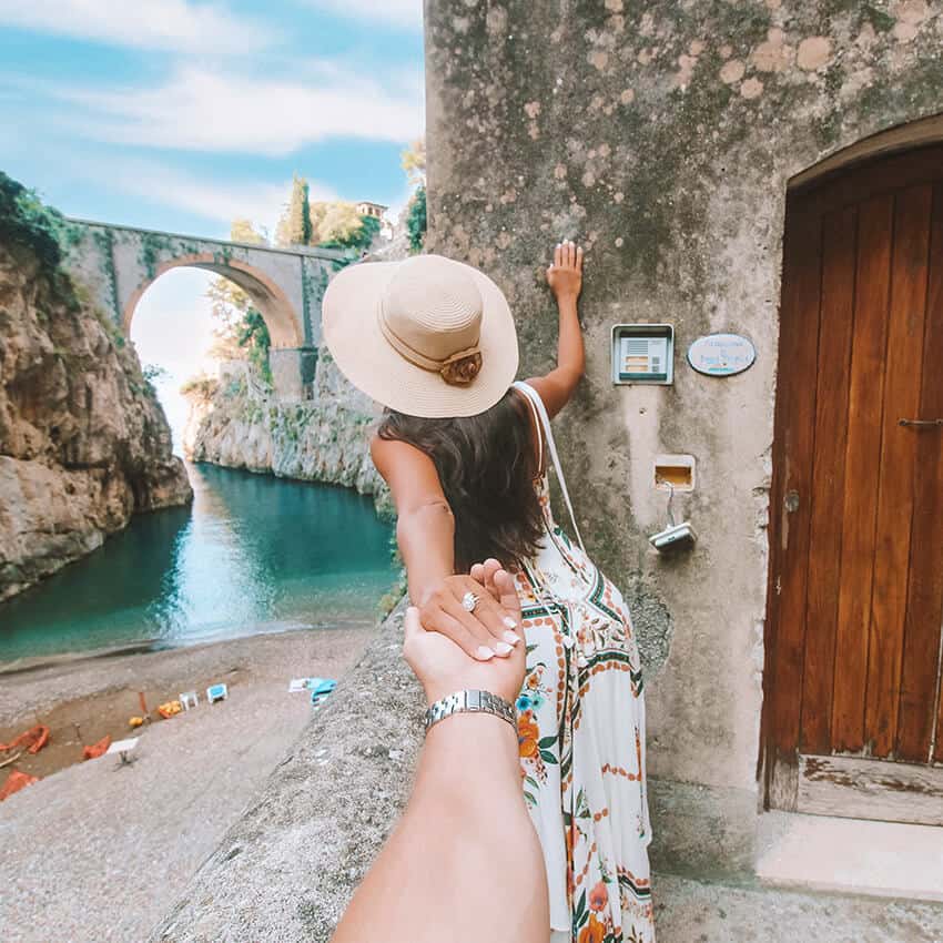 Ragazza con cappello a tesa larga tiene la mano del fidanzato e osserva il fiordo di Furore sulla Costiera Amalfitana