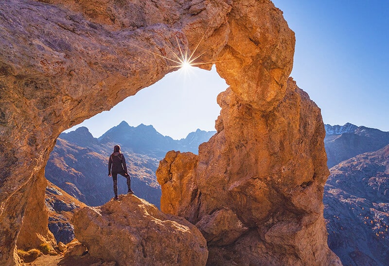 Donna fa trekking sotto un arco in pietra a Canyonlands nello Utah (USA)