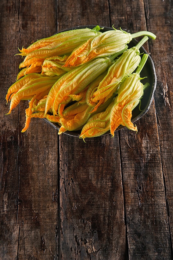 Un cestino di fiori di zucca freschi su un tavolo in legno
