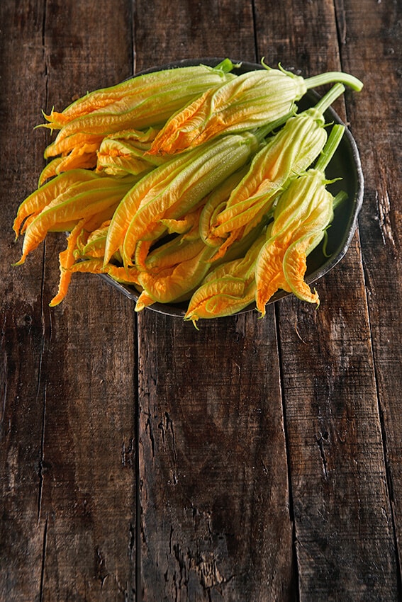 Un cestino di fiori di zucca freschi su un tavolo in legno