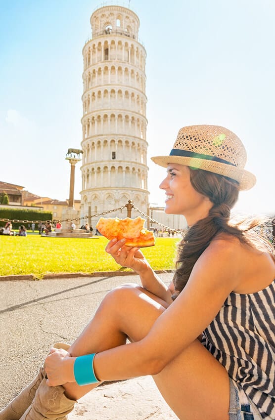 Ragazza mangia una pizza margherita in estate davanti alla torre pendente di Pisa
