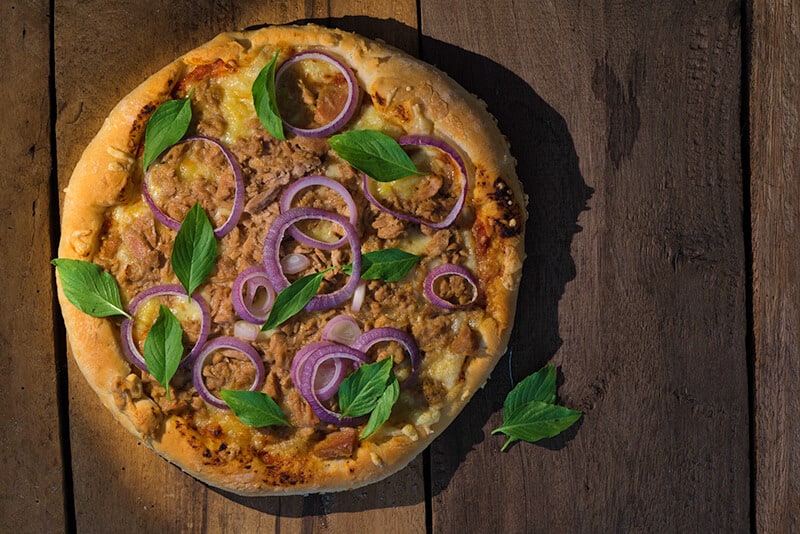 Italian pizza with tuna, onions and fresh basil leaves