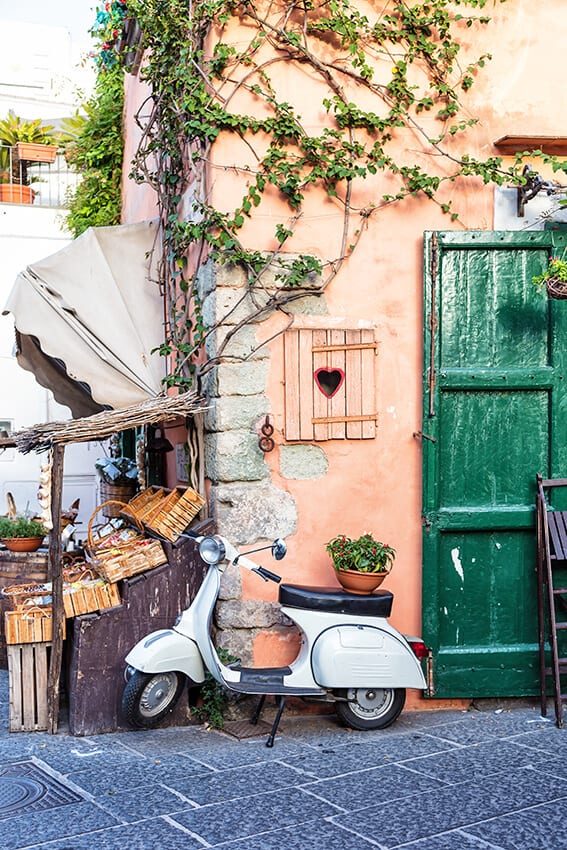 White Italian Vespa near a traditional building in the island of Procida (Italy)