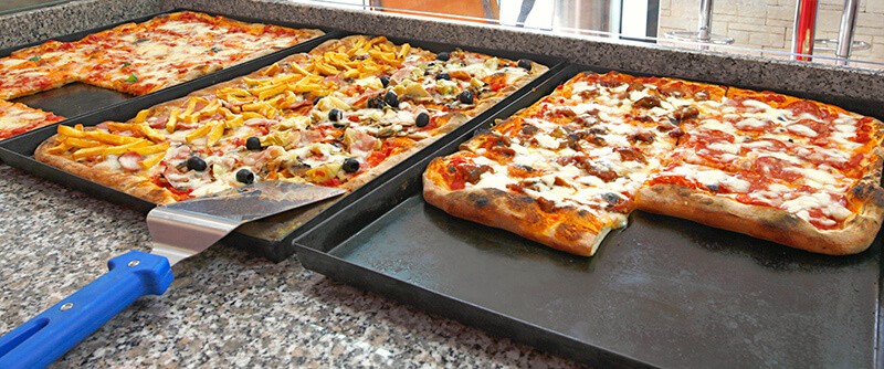 Diversi tipi di pizza al trancio in vetrina