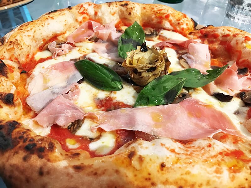 Close up of a traditional pizza capricciosa in Naples with a small artichoke on the top