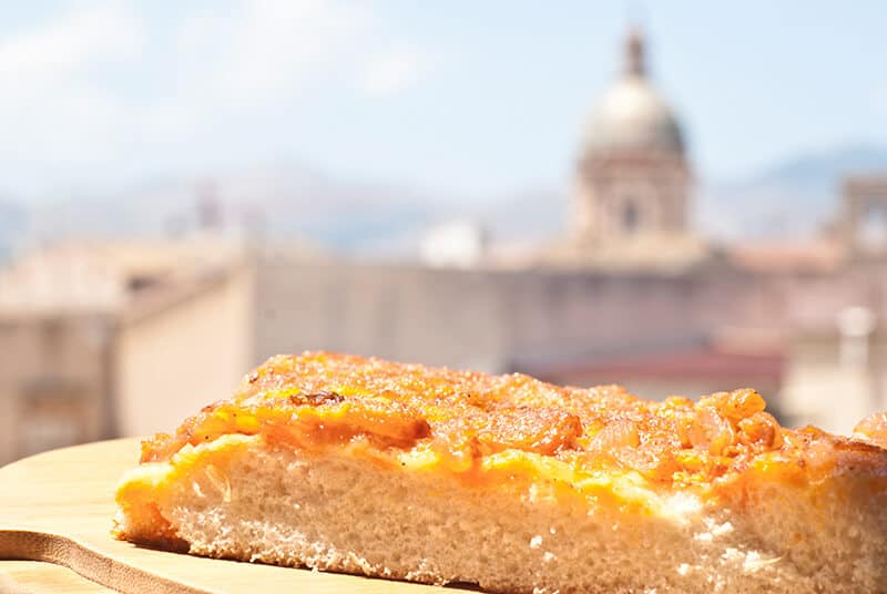 Sicilian pizza with the dome of a Church in the background