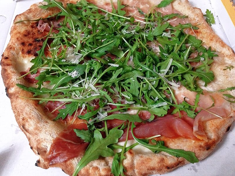 One of the types of Italian pizza with prosciutto and fresh arugula on the top