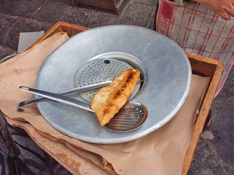 Una pizza fritta appena preparata da un venditore ambulante a Napoli