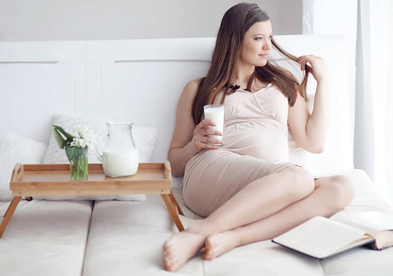 Donna incinta stesa a letto guarda fuori dalla finestra