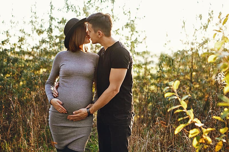 Young couple kissing while celebrating their pregnancy