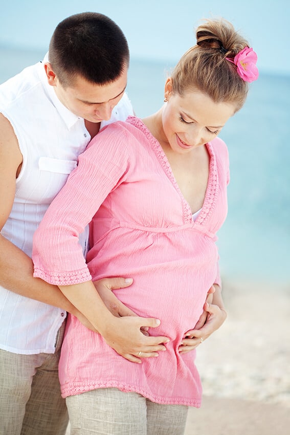 Coppia in attesa di un bambino festeggia in spiaggia