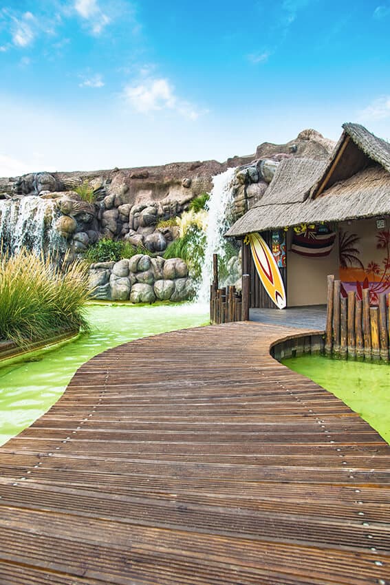 Wooden bridge over water with cute huts and surf tables