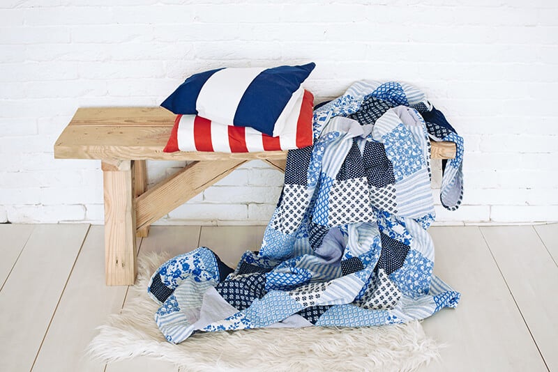 Hawaiian quilt and a couple of striped pillows on a wooden bench