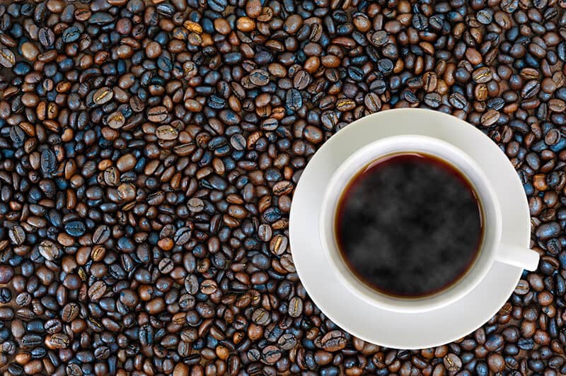 Chicchi di caffè tostato e una tazza di caffè Kona