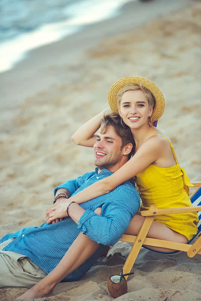 Newlyweds smiling and hugging on a beach