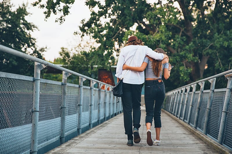Giovane coppia passeggia su un ponte metallico al tramonto
