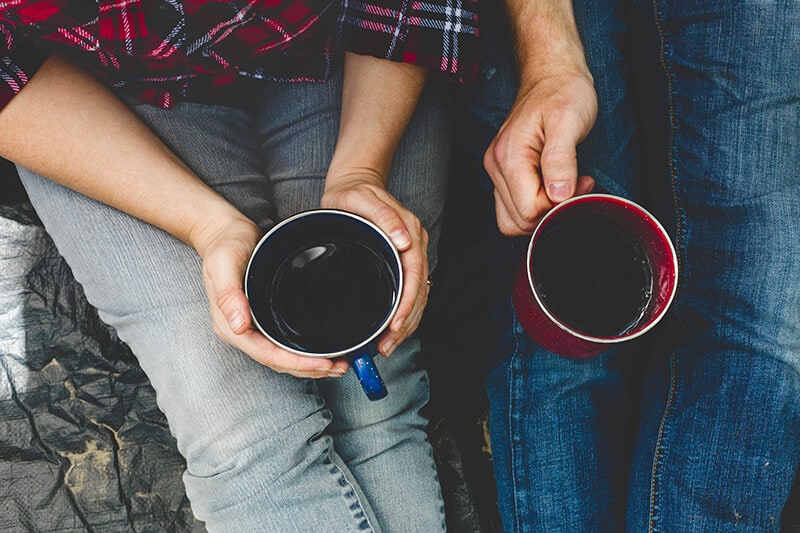 Man and woman on a trip together hold their cups of black coffee