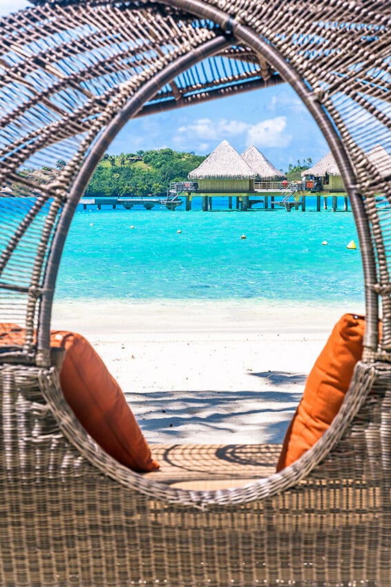 Two teal pillows set on wicker chairs overlooking the ocean at Nassau