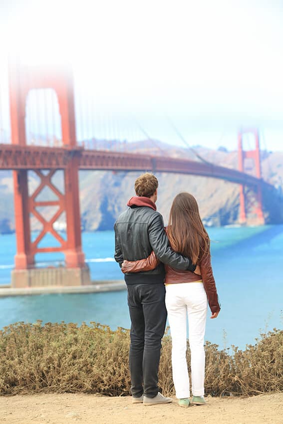 Coppia di giovani in viaggio a San Francisco davanti al Golden Gate Bridge