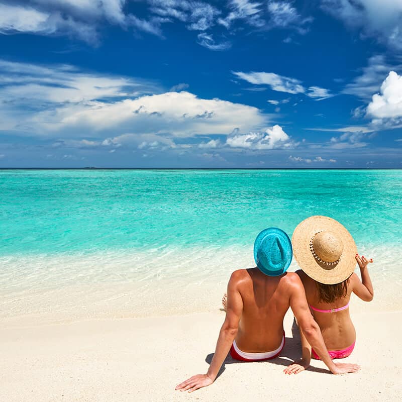 Coppia di turisti seduti su una spiaggia tropicale