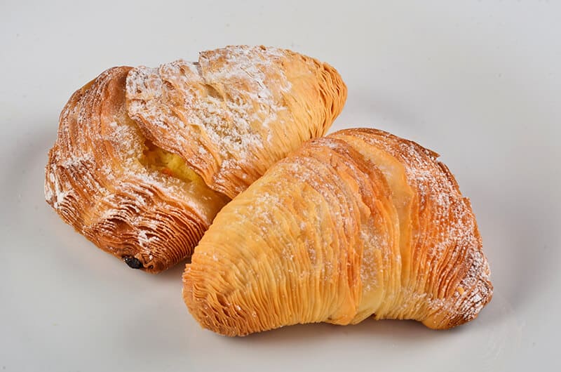 Two Neapolitan sfogliatella riccia on a white ceramic plate