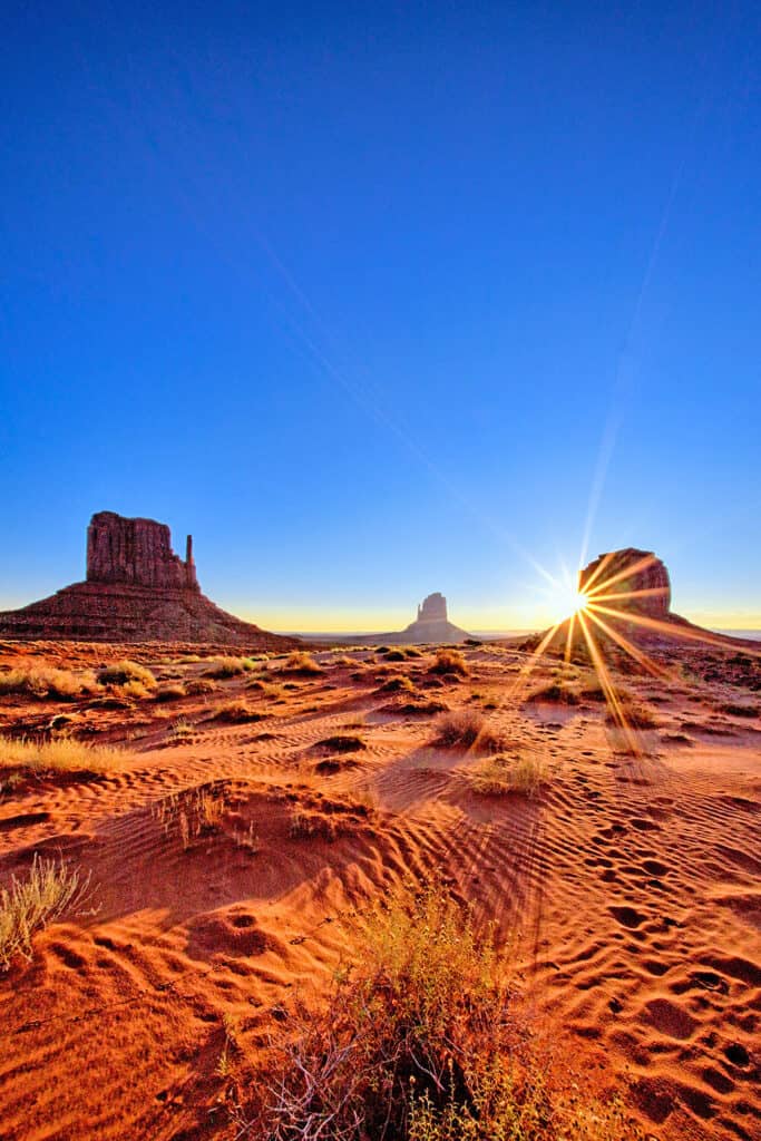 View of the most famous buttes in Monument Valley with sun rays in the background