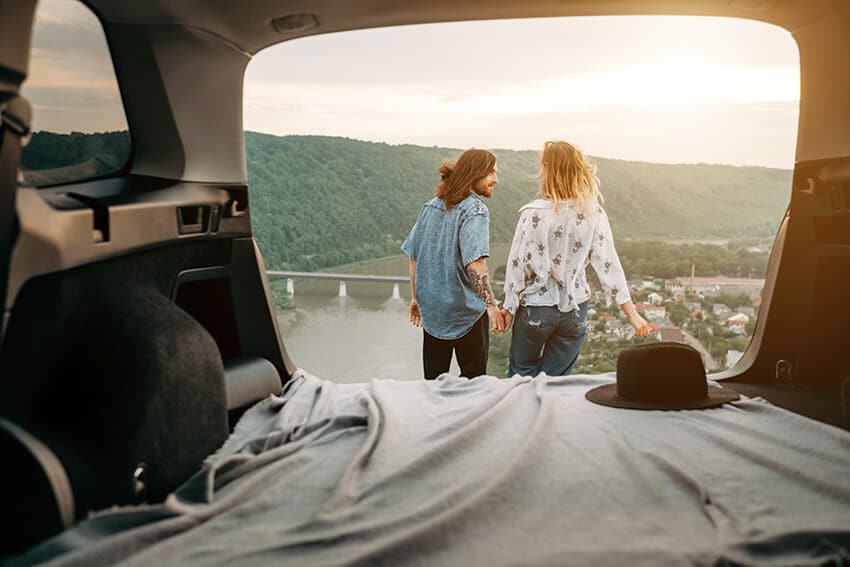 Couple holding hands seen from a car trunk with an air mattess inside