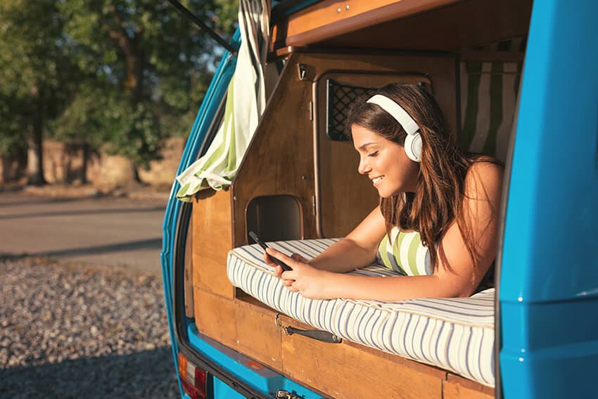 Girl listening to music laying down on a bed in a car