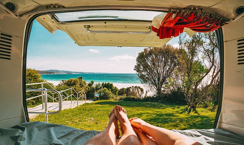 Couple laying in a van on a beach