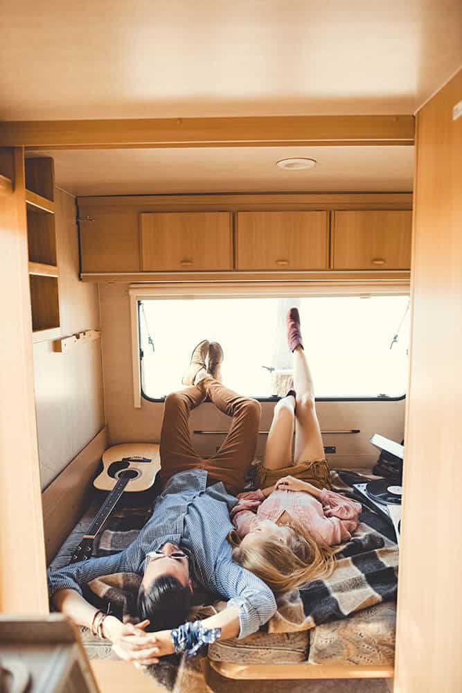 Couple laying down in the back of a van on a mattress