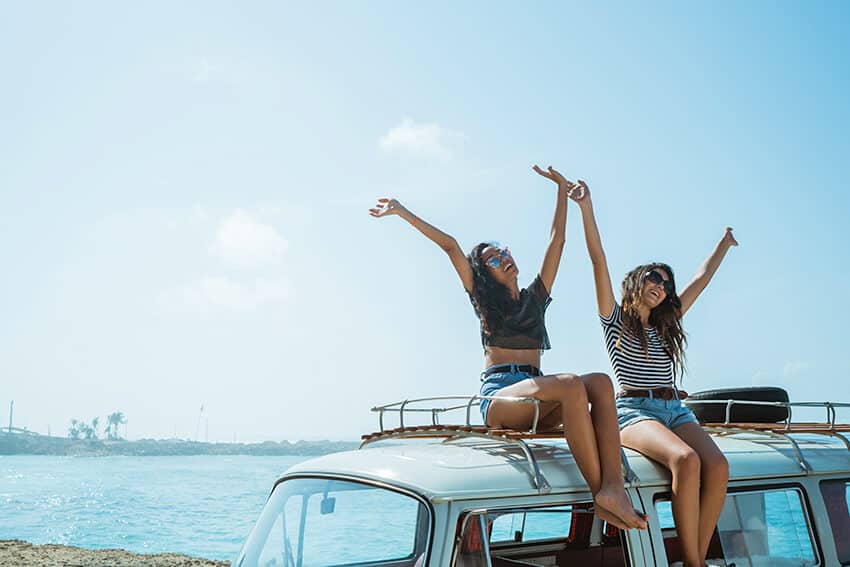 ragazze sedute sul tetto di un furgoncino in spiaggia