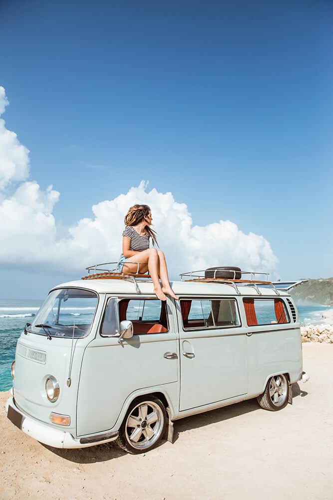 Ragazza seduta su un minivan in spiaggia